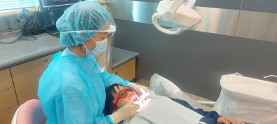 A dental therapist is undertaking oral examination.